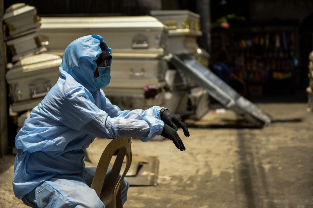 A worker in a protective suit, used due to the COVID-19 coronavirus outbreak, waits outside the crematorium facility as the cremation process takes some two hours in Manila on April 29, 2020.  AFP / Maria TAN
