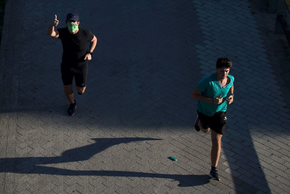 A man gives a thumbs-up as he runs in Seville on May 2, 2020, during the hours allowed by the government to go out and exercise, for the first time since the beginning of a national lockdown to prevent the spread of the COVID-19 disease. AFP / CRISTINA QU