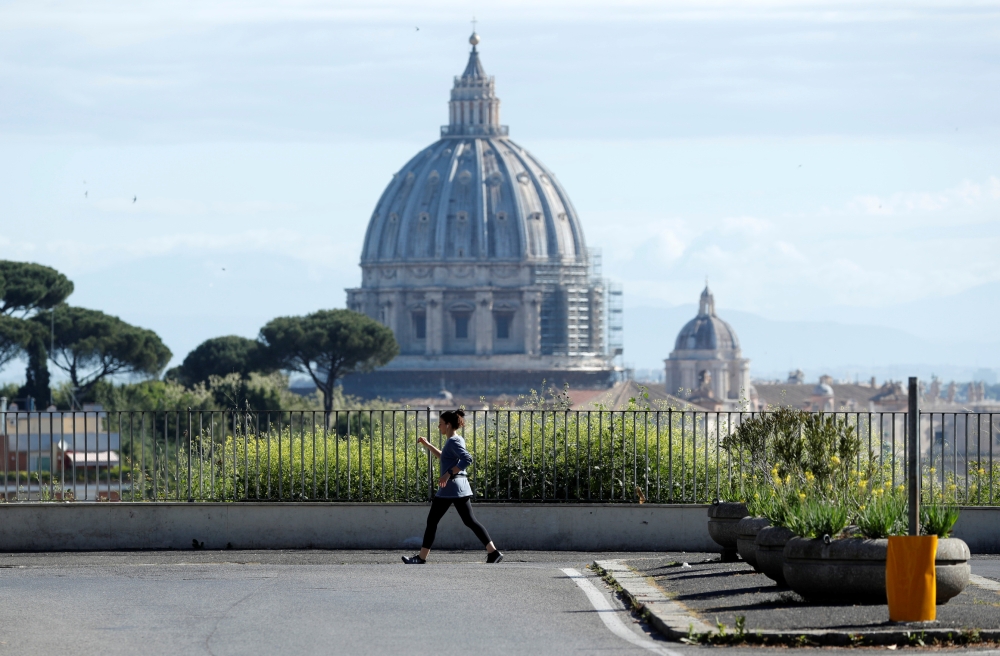 A woman walks with St. Peter's Basilica in the background, ahead of Pope Francis' Regina Coeli prayer which is to be held at the Vatican without public participation due to the coronavirus disease (COVID-19) outbreak, in Rome, Italy, May 3, 2020. REUTERS/