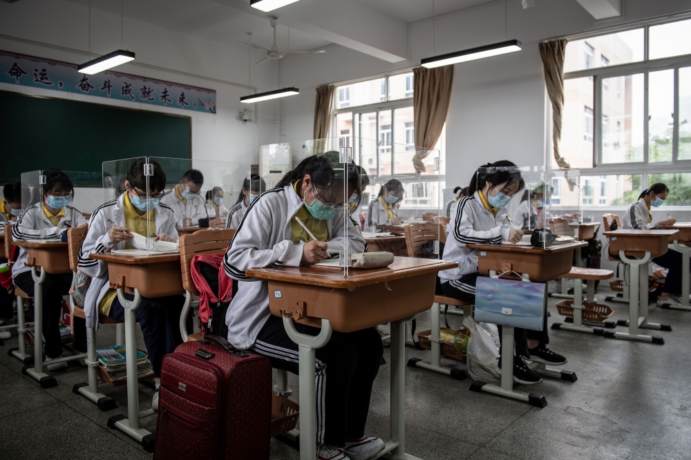 High school senior students study with plastic partitions in a classroom in Wuhan in China's central Hubei province on May 6, 2020. Senior school students in 121 institutions were back in front of chalk boards and digital displays for the first time on Ma