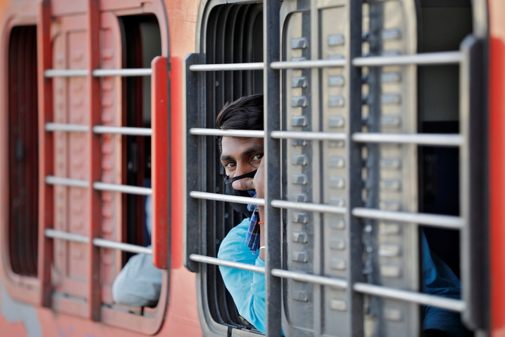 A migrant worker, who was stranded in the western state of Gujarat due to a lockdown imposed by the government to prevent the spread of the coronavirus disease (COVID-19), looks out from a window of a train that will take him to his home state of Uttar Pr