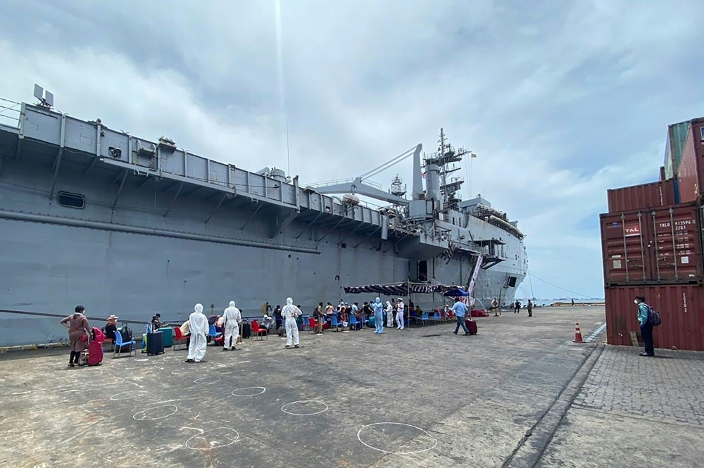 In this handout photograph taken on May 8, 2020 and released by the Maldives Ports Limited, officials wearing protective gear check Indian citizens before boarding the INS Jalashwa ship to be evacuated to India, as part of a massive repatriation effort du