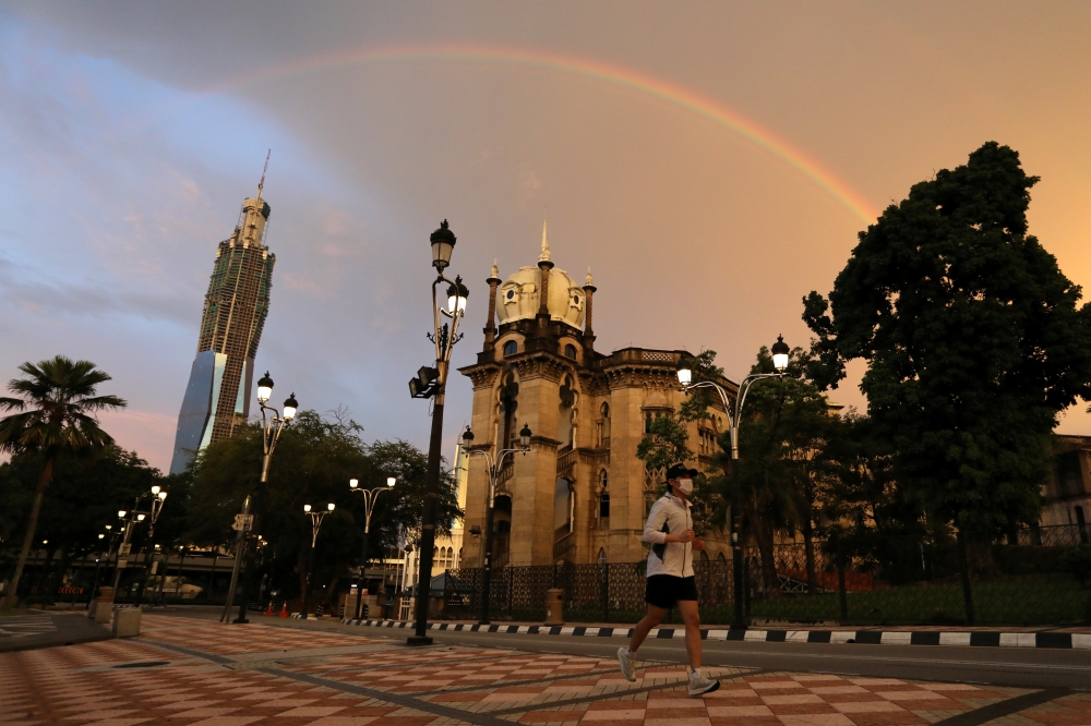 A man wearing protective face mask jogs under a rainbow as Malaysia reopens a majority of businesses, after a movement control order was imposed to fight the outbreak of the coronavirus disease (COVID-19), in Kuala Lumpur, Malaysia May 4, 2020. REUTERS/Li