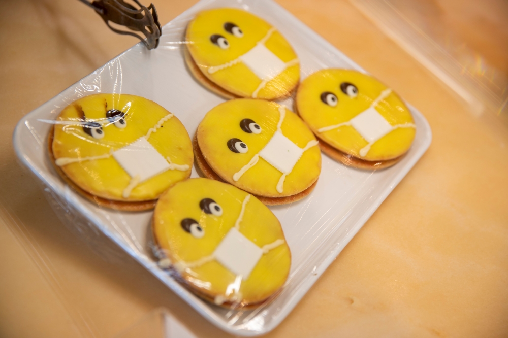 A tray of cookies decorated with faces wearing masks is being placed in the cake stand at the reopened Cafe Prag in Schwerin, northeastern Germany on May 9, 2020 amid the ongoing Covid-19, coronavirus pandemic. AFP / Odd ANDERSEN
