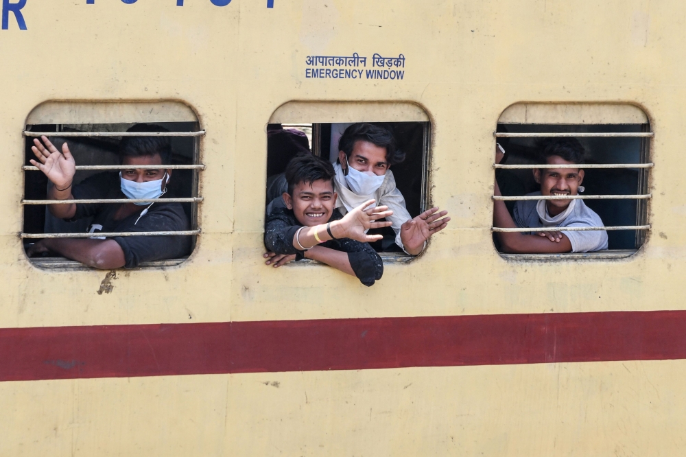 Migrant workers and families wave from the windows of a special train from Amritsar to Barauni of Bihar state as they go back to their hometowns after the government eased a nationwide lockdown imposed as a preventive measure against the COVID-19 coronavi