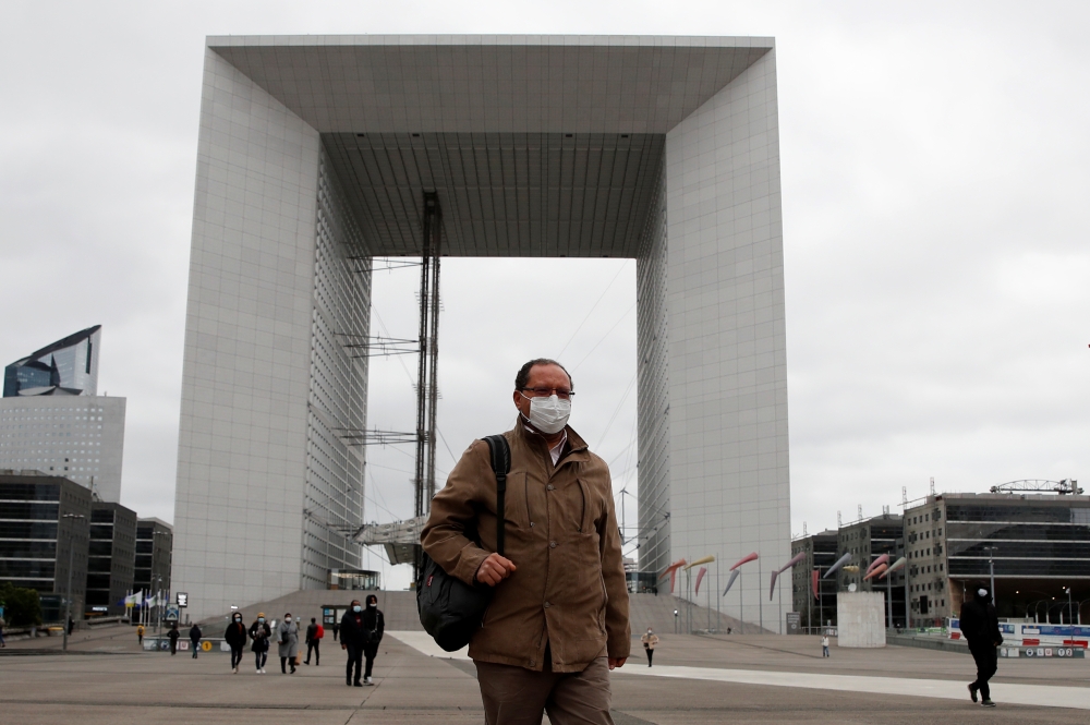 People wearing protective face masks walk at the financial and business district of La Defense near Paris as France begun a gradual end to a nationwide lockdown due to the coronavirus disease (COVID-19), May 11, 2020. REUTERS/Gonzalo Fuentes