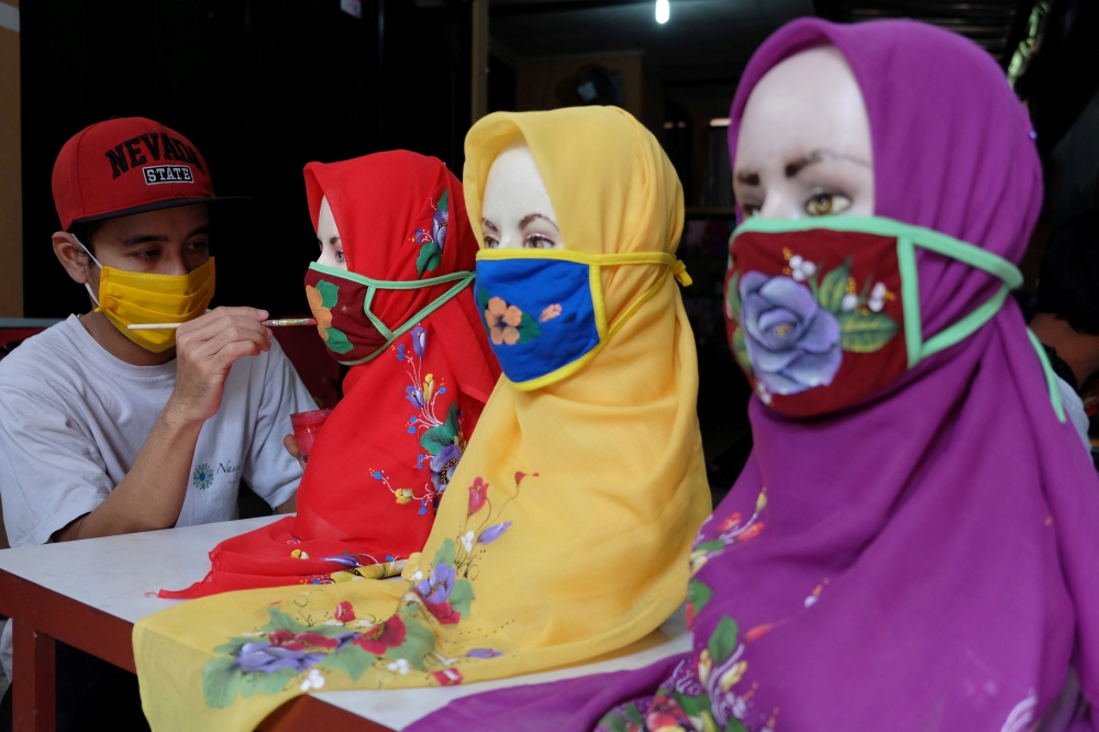 :A worker draws on protective masks amid the coronavirus disease (COVID-19) outbreak in Solo, Central Java Province, Indonesia May 6, 2020, in this photo taken by Antara Foto. Antara Foto/Maulana Surya/ via REUTERS ATTENTION EDITORS - THIS IMAGE WAS PROVI