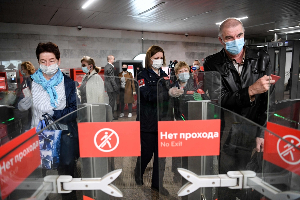 People wearing face masks walk through ticket gates at Savyolovskaya metro station on the first day of mandatory use of masks and gloves on Moscow public transport, in Moscow on May 12, 2020, amid the coronavirus pandemic. / AFP / Kirill KUDRYAVTSEV
