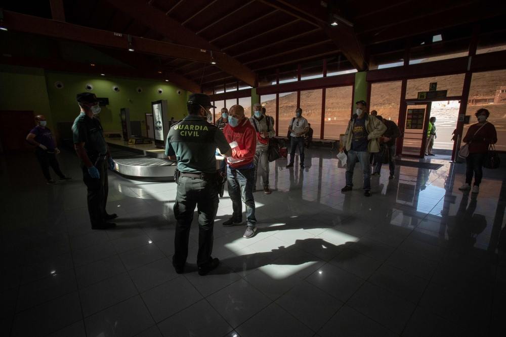 Spanish Civil Guards check documents allowing passengers to travel at Los Cangrejos airport on the Canary Island of El Hierro on May 11, 2020. Spaniards returned to outdoor terraces at cafes and bars as around half of the country moved to the next phase o