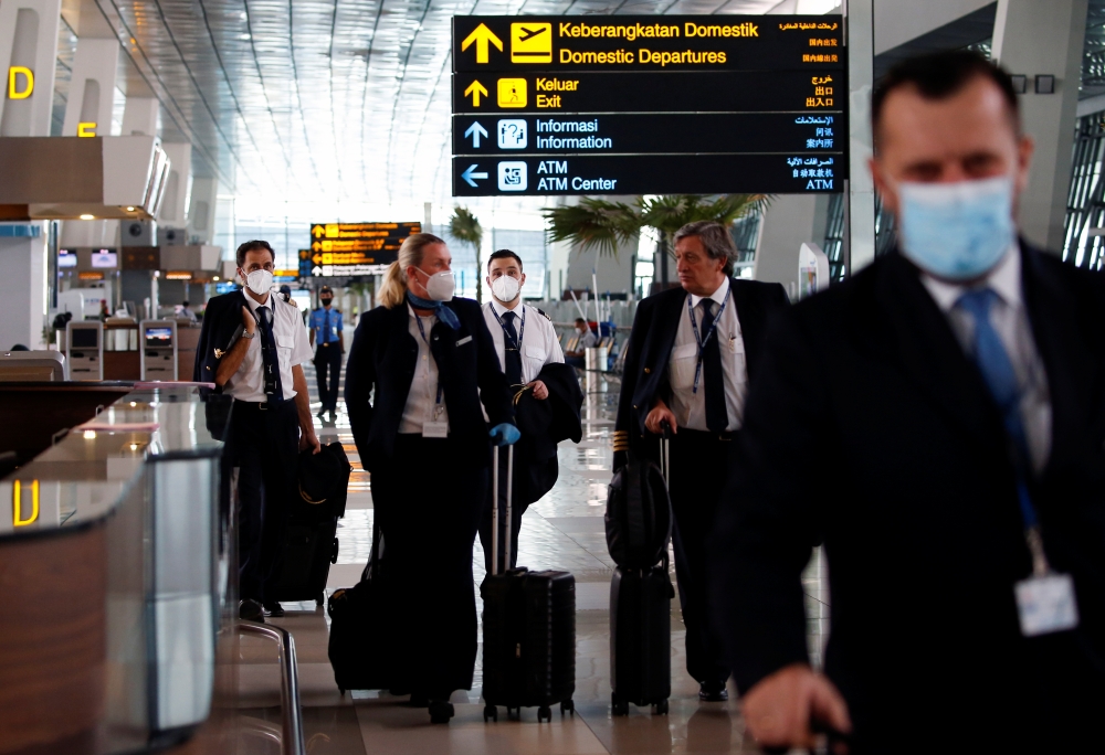 Crew members wearing protective masks carry their luggage at the Soekarno-Hatta International Airport, amid the spread of coronavirus disease (COVID-19) outbreak, in Tangerang near Jakarta, Indonesia, May 12, 2020. REUTERS/Willy Kurniawan