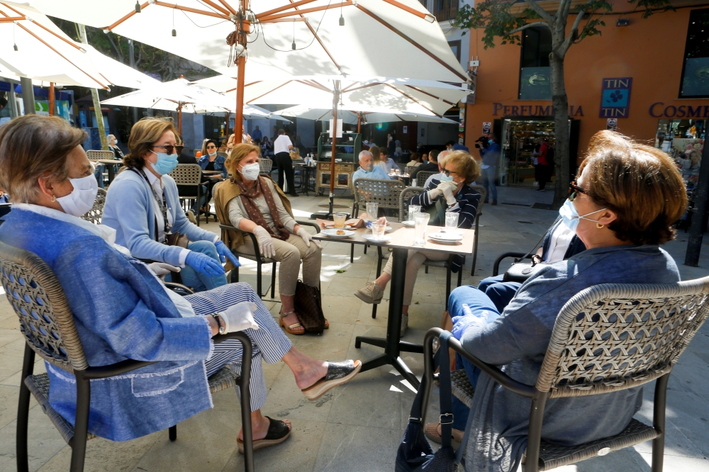 People take a coffee in a bar as some Spanish provinces are allowed to ease restrictions during the phase one, amid the coronavirus disease (COVID-19) outbreak, in Palma de Mallorca, Spain, May 11, 2020. REUTERS/Enrique Calvo
