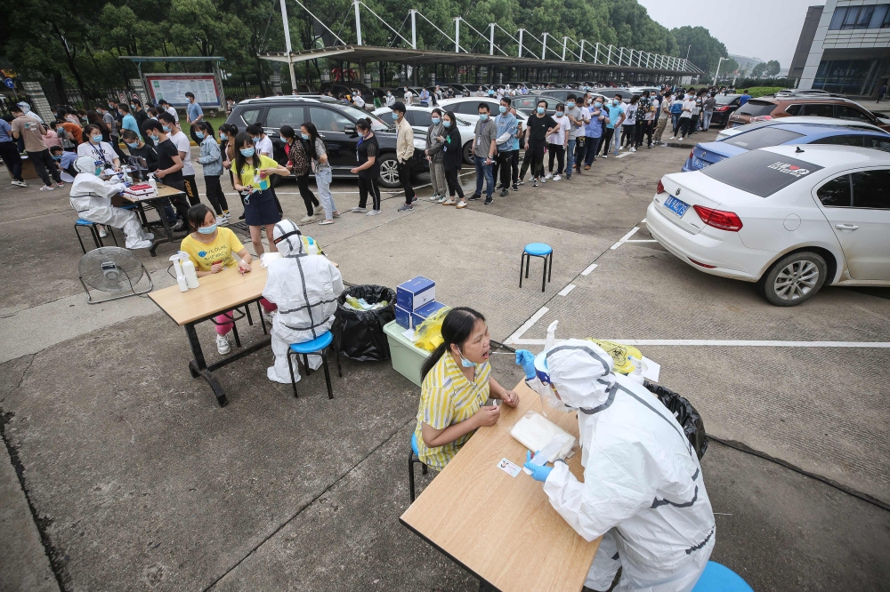 Medical workers take swab samples from staff members from the AOC computer monitor factory to be tested for the COVID-19 coronavirus in Wuhan in China's central Hubei province on May 15, 2020. Nervous residents of China's pandemic epicentre of Wuhan queue