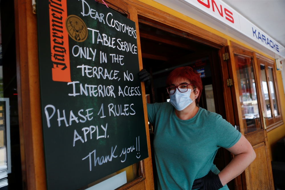 Toni, 45, owner of a pub in Magaluf beach wearing face mask and gloves poses next to a board with the rules to be applied during the reopening of commercial activity after the coronavirus disease (COVID-19) outbreak in Palma de Mallorca, in Mallorca Spain