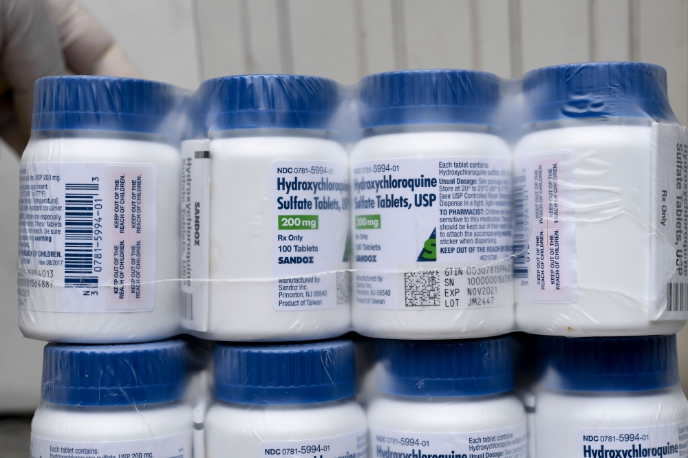 :(FILES) In this file photo taken on April 21, 2020 a Salvadoran Health Ministry worker shows a package of bottles of HydroxyChloroquine pills to be distributed in hospitals in San Salvador, amid the COVID-19 coronavirus outbreak.  / AFP / Yuri CORTEZ
