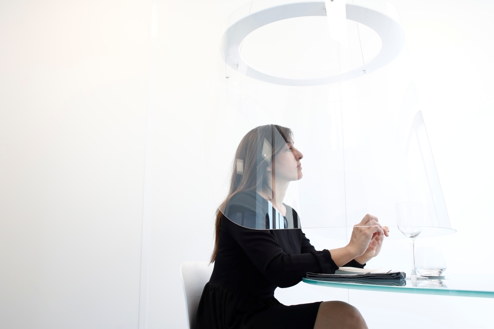 A woman poses under a Plex'Eat prototype plexiglas bubble by designer Christophe Gernigon which surrounds diners to protect them from the novel coronavirus during a presentation in Cormeilles-en-Parisis, near Paris, as restaurants in France prepare to re-