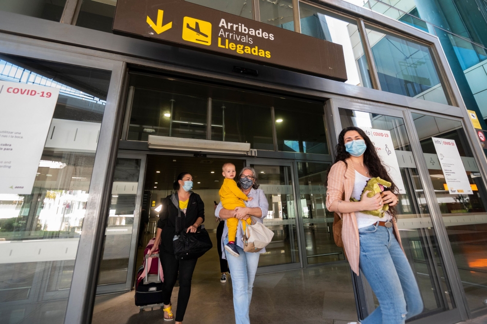 Passengers who were on board a Swiss Air flight from Zurich and who will be put in quarantine arrive at the airport in Valencia on May 21, 2020. / AFP / STR / JOSE JORDAN
