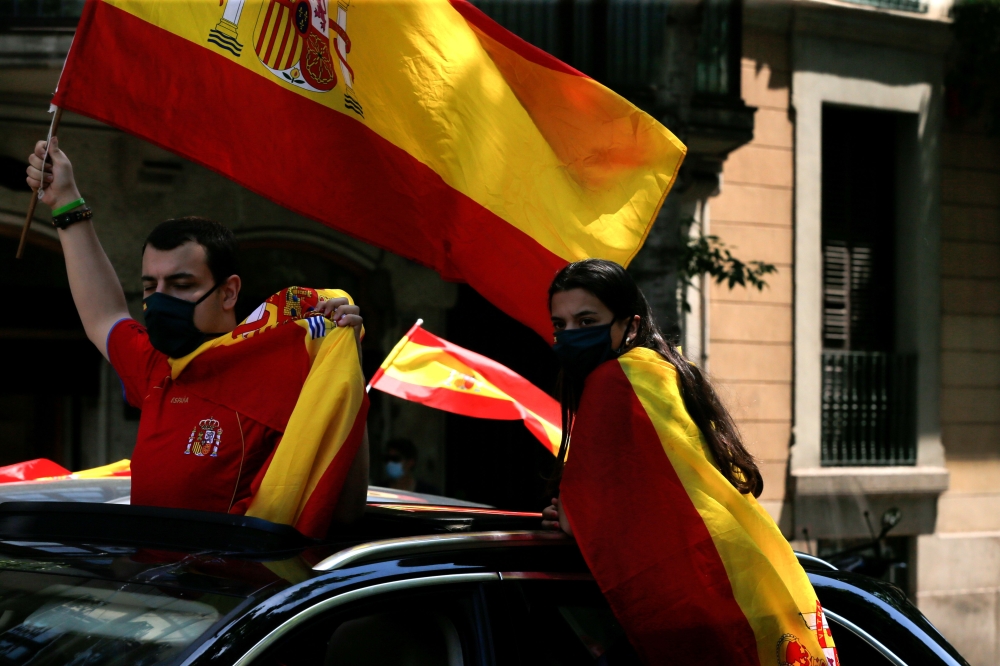 Demonstrators wave Spanish flags from their car during a 