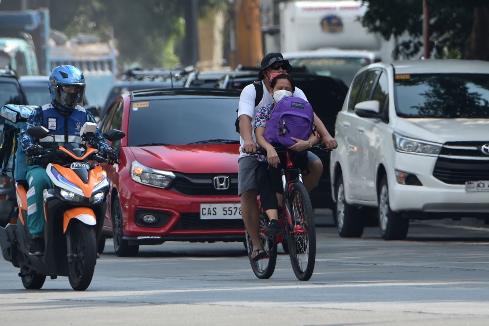A couple ride on bicycle on a road in Manila on May 20, 2020. Bicycle sales have skyrocketed with some shops selling 300-400 units over the past two days since the Philippine government began easing quarantine measures to curb the spread of the COVID-19 c