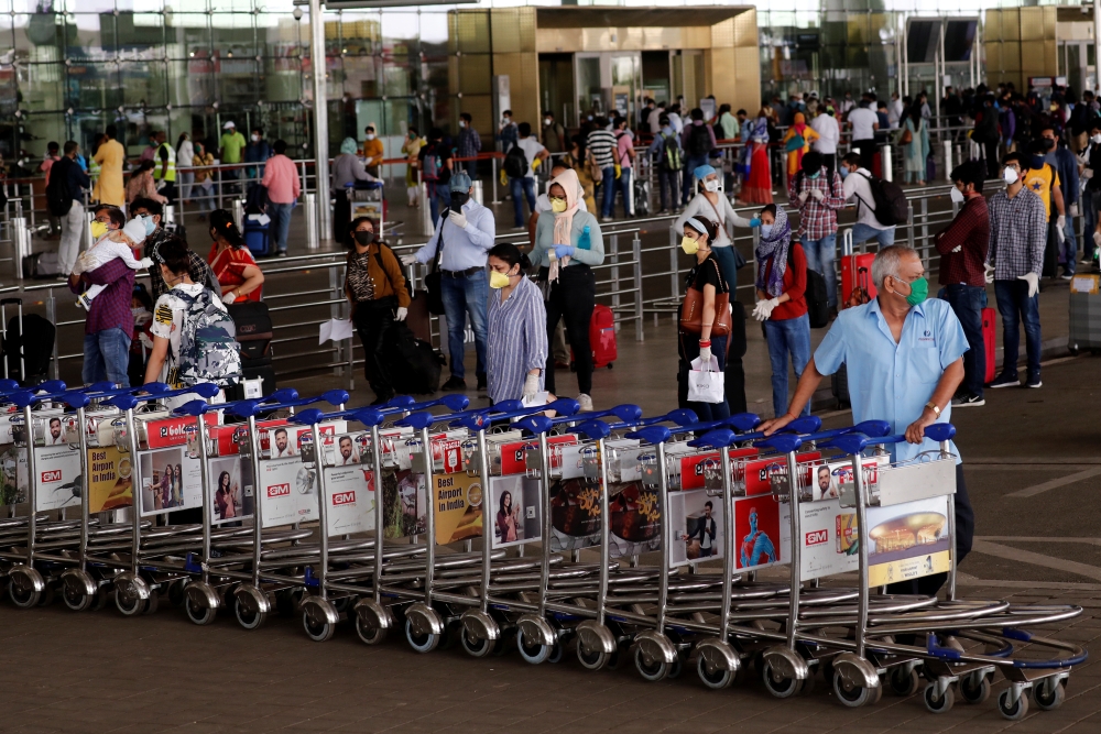 An airport staff member pushes trollies at the entrance of Chhatrapati Shivaji International Airport, after the government allowed domestic flight services to resume, during an extended nationwide lockdown to slow the spread of the coronavirus disease (CO