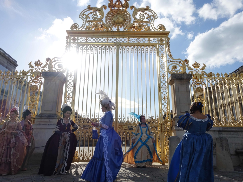 (FILES) In this file photograph taken on June 1, 2015, women dressed in period costume wait for the gates of the 