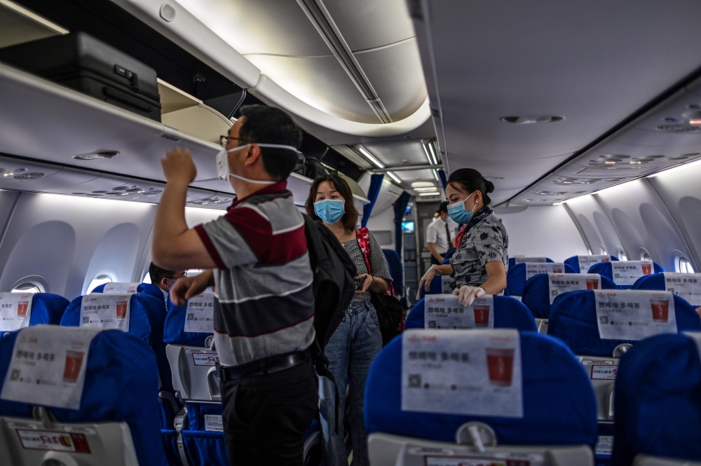 Passengers wearing facemasks board a flight to Shanghai at Tianhe Airport in Wuhan, in China’s central Hubei province on May 29, 2020. / AFP / Hector RETAMAL
