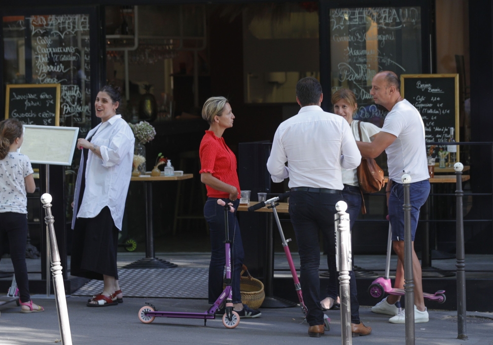 People stand and drink outside a cafe in Paris on May 29, 2020, ahead of the re-opening of the French capital's cafe terraces, scheduled for June 2, as France eases lockdown measures taken to curb the spread of the COVID-19 pandemic, caused by the new cor