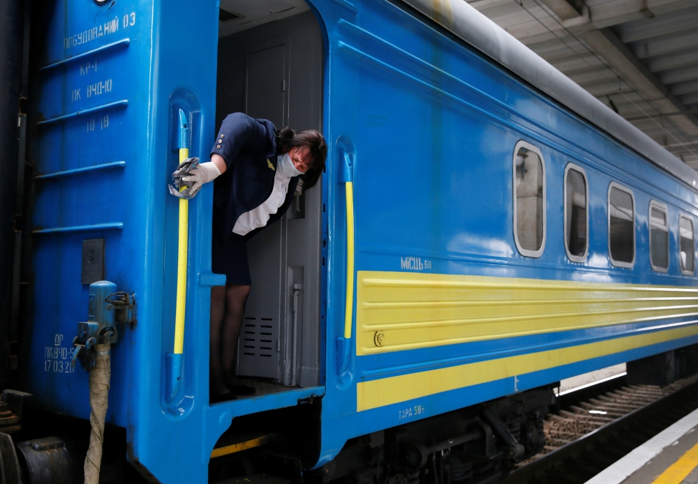 A conductor cleans handrails of a train upon the arrival at the central railway station, after train services were resumed as part of another stage to ease the coronavirus disease (COVID-19) restrictions in Kiev, Ukraine June 1, 2020. REUTERS/Gleb Garanic