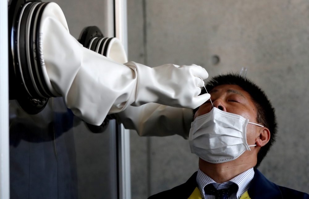 FILE PHOTO: A medical worker conducts a simulation for a walk-in style polymerase chain reaction (PCR) test for the coronavirus disease (COVID-19), at a makeshift facility in Yokosuka, south of Tokyo, Japan, April 23, 2020. REUTERS/Issei Kato/File Photo
