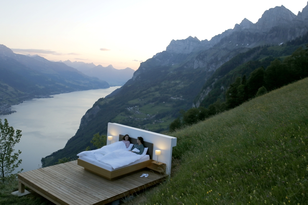 Dominic Gregorin and Anja Wachter (L) pose in the bedroom of the Zero-Real-Estate land art installation by Swiss artists Frank and Patrik Riklin, as the outbreak of the coronavirus disease (COVID-19) continues, on an alp in front of the Churfirsten mounta