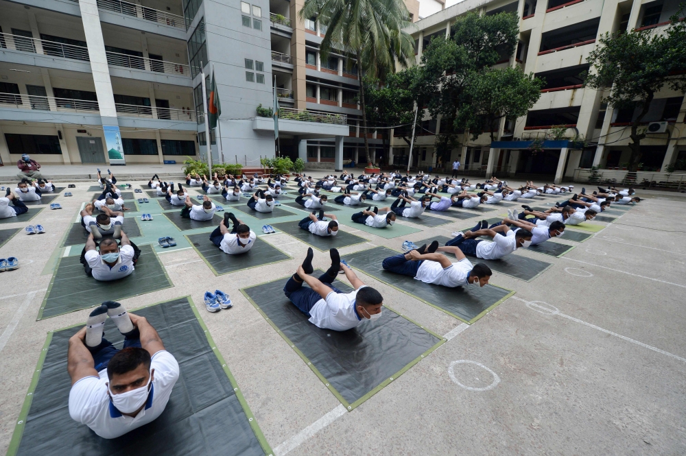 Members of the Bangladesh police attend a yoga session to boost the immune system of police personnel during the COVID-19 coronavirus pandemic, in Dhaka on July 8, 2020. / AFP / Munir UZ ZAMAN