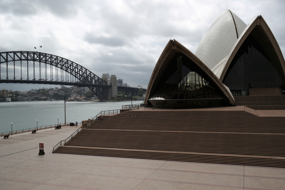 FILE PHOTO: People are seen on the nearly deserted steps of the Sydney Opera House, in the wake of New South Wales implementing measures shutting down non-essential businesses and moving toward harsh penalties to enforce self-isolation as the spread of co
