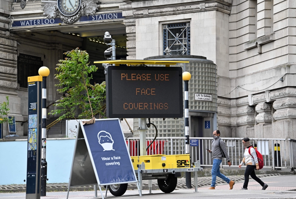 A sign tells passengers to 'wear a face covering' at Waterloo train station in central London , on June 8, 2020, as the UK government's planned 14-day quarantine for international arrivals to limit the spread of the novel coronavirus COVID-19 begins. / AF