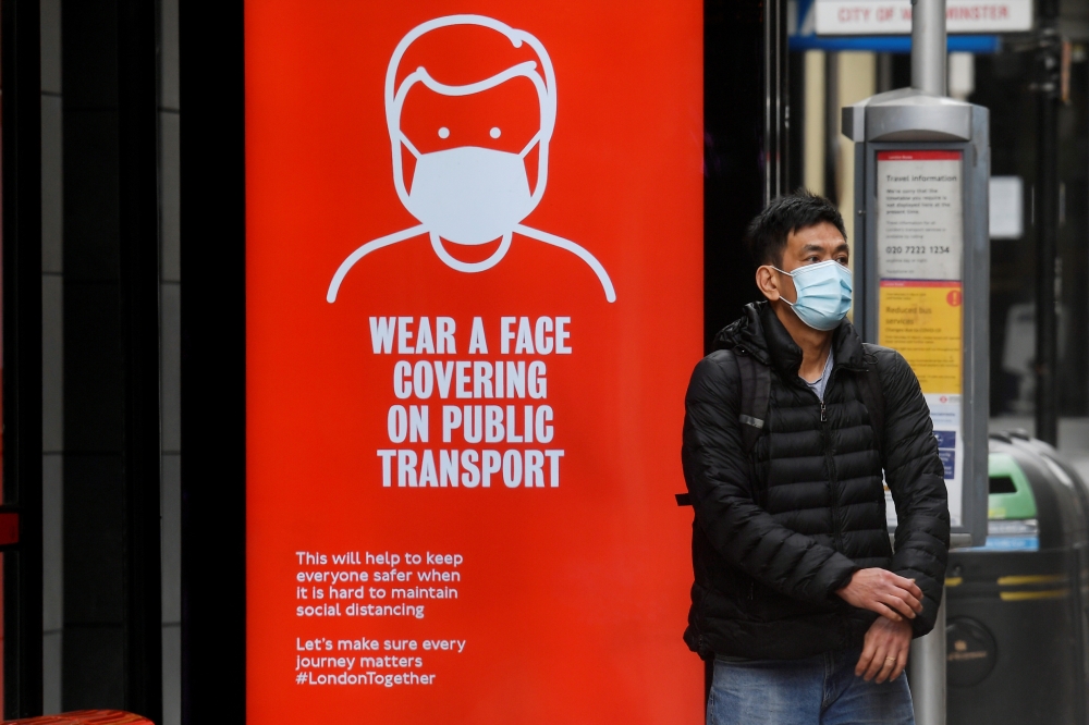 FILE PHOTO: A man wearing a mask waits at a bus stop in London, following the outbreak of the coronavirus disease (COVID-19), London, Britain, June 5, 2020. REUTERS/Toby Melville/File Photo
