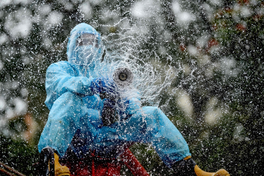 TOPSHOT - A firefighter sprays disinfectant as a preventive measure against the spread of the COVID-19 coronavirus in a containment zone in Chennai on May 11, 2020. / AFP / Arun SANKAR

