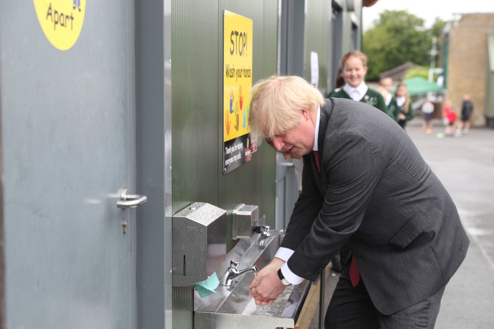 Britain's Prime Minister Boris Johnson washes his hands at a sink in the playground during a visit to Bovingdon Primary School in Bovingdon, Hemel Hempstead, Hertfordshire on June 19, 2020. AFP / POOL / Steve Parsons