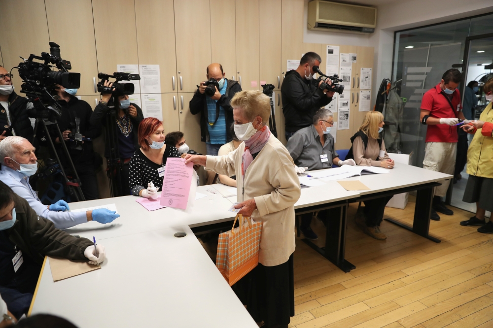 A voter wearing a face mask collects ballot papers during national election, the first in Europe since coronavirus lockdown, at a polling station in Belgrade, Serbia, June 21, 2020. REUTERS/Marko Djurica