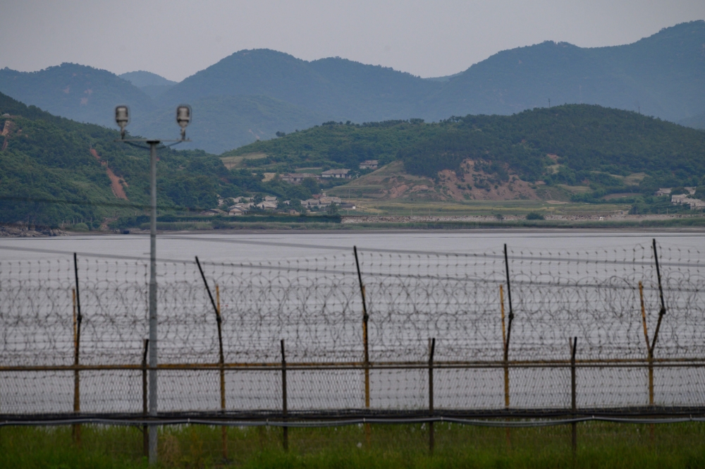 A general view shows the skyline of North Korea behind the barbed-wire fence of the Demilitarized Zone (DMZ) separating North and South Korea, on the South Korean island of Gyodong on June 18, 2020.   AFP / Ed JONES
