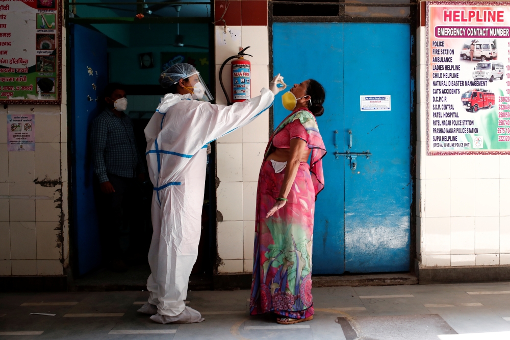 A medical worker collects a sample from a woman at a school turned into a centre to conduct tests for the coronavirus disease (COVID-19), amidst its spread in New Delhi, India June 22, 2020. REUTERS/Adnan Abidi