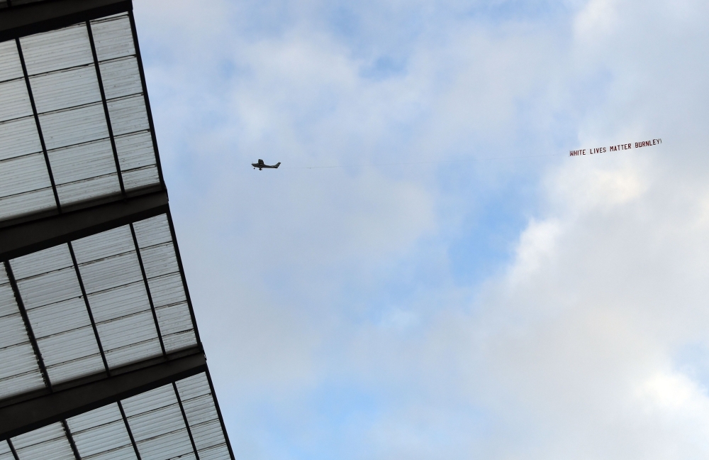 A plane towing a banner reading 'White Lives Matter Burnley' is seen in the sky above the stadium during the English Premier League football match between Manchester City and Burnley at the Etihad Stadium in Manchester, north west England, on June 22, 202