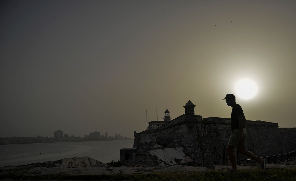 A man walks near Morro Castle as a vast cloud of Sahara dust is blanketing the city of Havana on June 24, 2020.  AFP / YAMIL LAGE