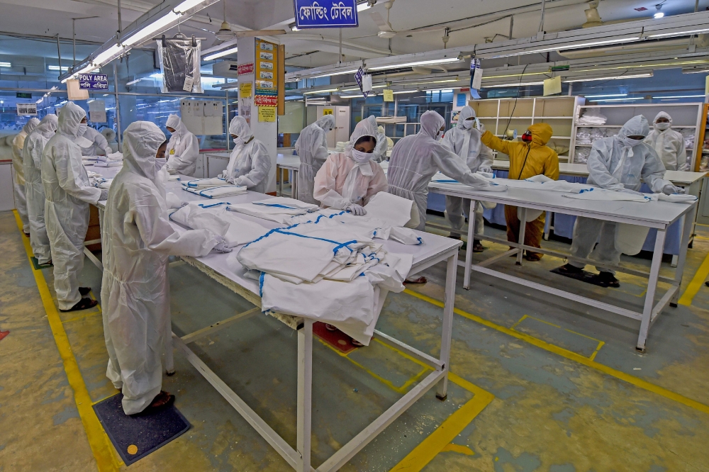 In this picture taken on June 18, 2020, labourers from Beximco Textiles Ltd manufacturer work on Personal Protective Equipment (PPE) garment used as a preventive measure against the COVID-19, in Savar on the outskirts of Dhaka. AFP / MUNIR UZ ZAMAN 