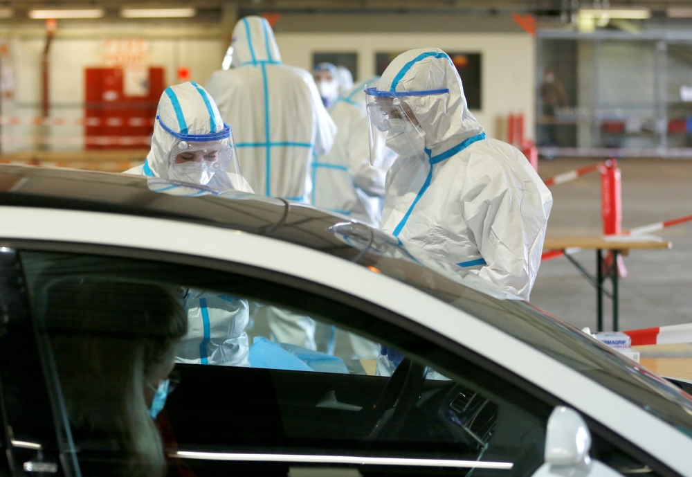 Medical personnel talk to a person at a drive-in testing site at an out-of-service aircraft hangar at Guetersloh Airport following an outbreak of the coronavirus disease (COVID-19) in Guetersloh, Germany, Germany June 27, 2020. REUTERS/Leon Kuegeler