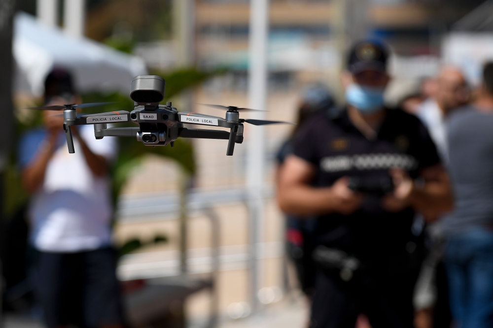A local police officer flies a drone warning people to respect safety rules on a beach in Lloret de Mar on June 22, 2020. AFP / Josep LAGO
