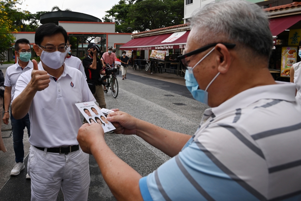 Singapore's Deputy Prime Minister Heng Swee Keat (L), of the incumbent People's Action Party, gives a thumbs up during a campaign walkabout in the Bedok South estate neighbourhood ahead of the general election in Singapore on July 8, 2020. / AFP / ROSLAN 