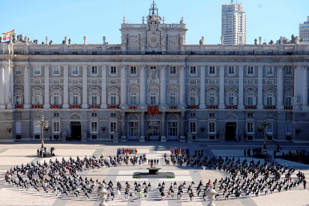 Attendees sit around a cauldron during a state ceremony to honour the 28,400 victims of the coronavirus crisis as well as those public servants who have been fighting on the front line against the pandemic in Spain, on July 16, 2020, at the Royal Palace i