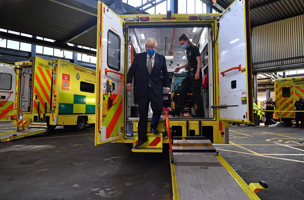 Britain's Prime Minister Boris Johnson (L), wearing a face mask or covering due to the COVID-19 pandemic, talks with a paramedic inside the back of an ambulance during his visit to the headquarters of the London Ambulance Service NHS Trust in central Lond