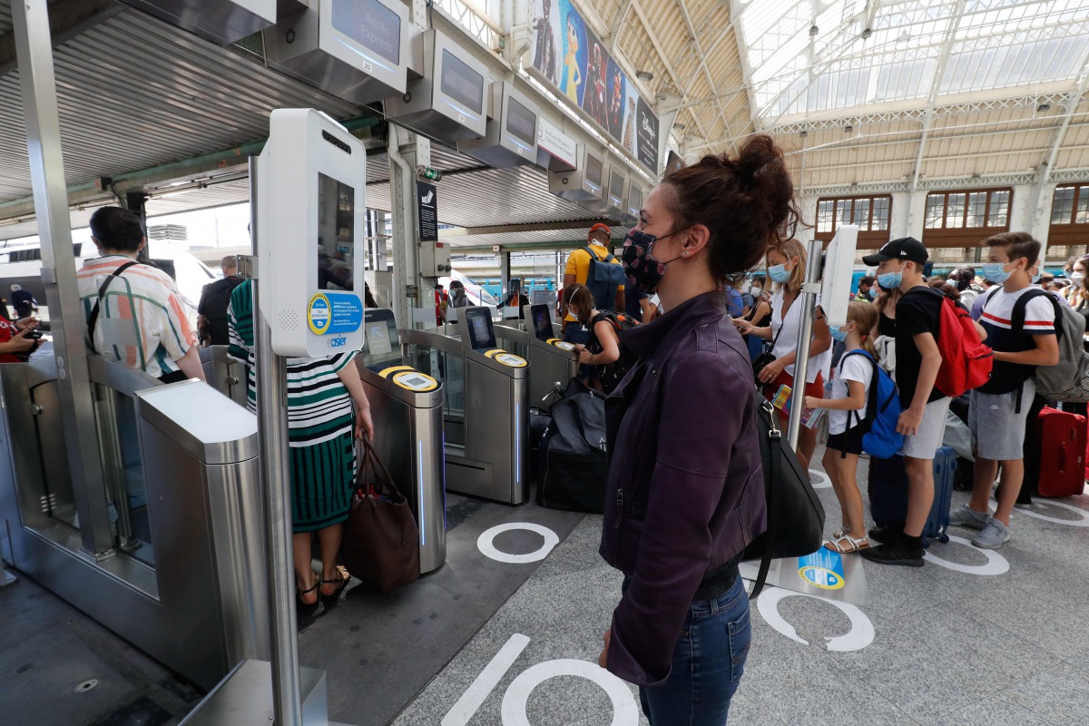 A traveller as her temperature checked at the security gate, prior to board a TGV high-speed train at the Gare de Lyon train station in Paris, on July 21, 2020, as part of sanitary measures taken to curb the spread of the COVID-19 pandemic, caused by the 
