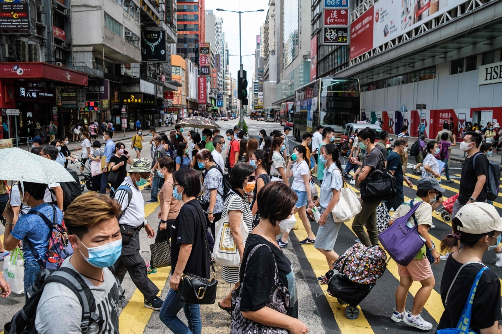 Pedestrians walk across a main road in Hong Kong on July 20, 2020. / AFP / ANTHONY WALLACE