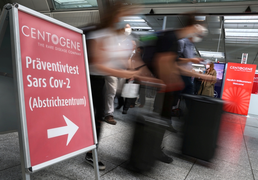 FILE PHOTO: Travellers rush past the entry of Germany's first walk-through the coronavirus disease (COVID-19) test center which is opened by diagnostics provider Centogene in cooperation with air carrier Lufthansa and Fraport at the airport in Frankfurt, 