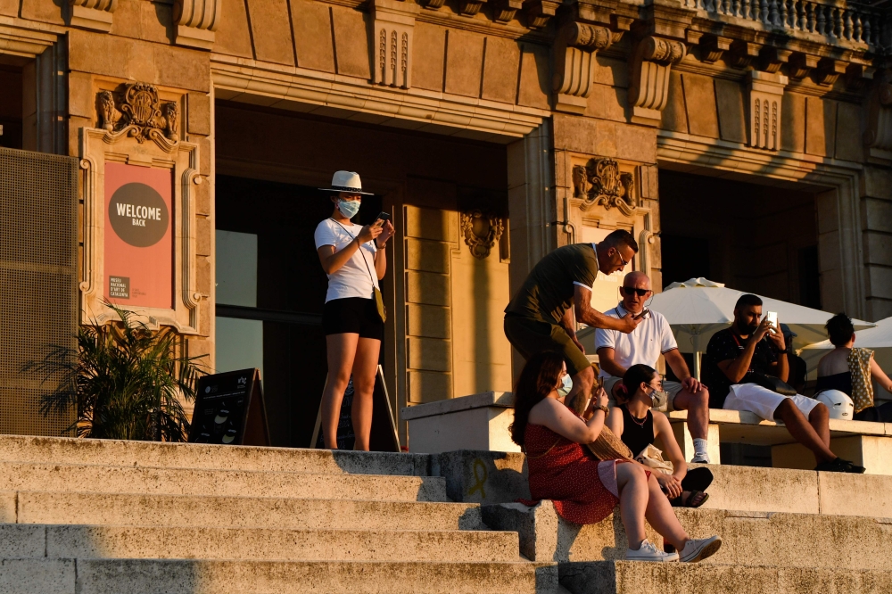 People sit on the stairs of the National Art Museum of Barcelona (MNAC) in Barcelona on July 25, 2020. / AFP / Pau BARRENA
